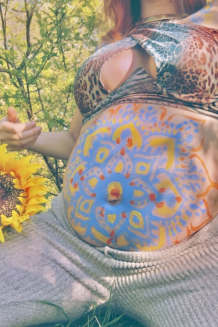 Blue and orange mandala on a pregnant belly outdoors