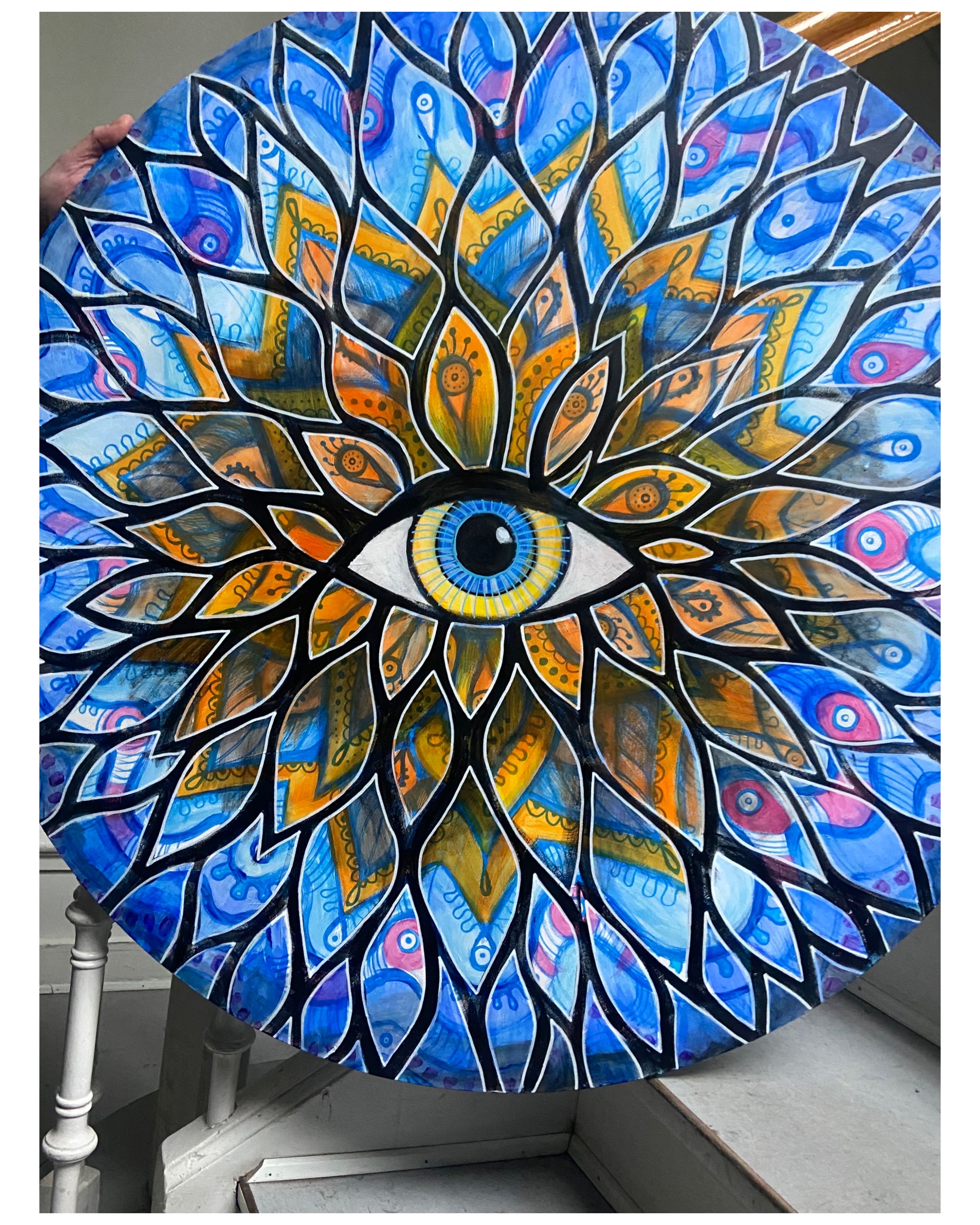 Circular mandala painting with eye at centre, blue and gold